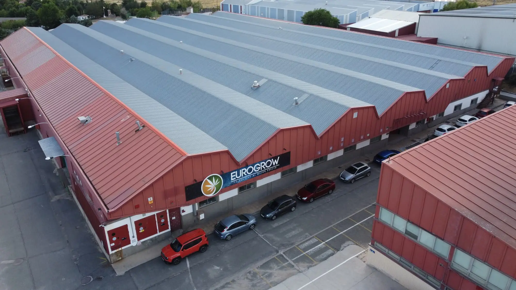 Nave Eurogrow Vista aérea de la nave/almacén de Eurogrow con el logo en la fachada y zona de aparcamiento exterior