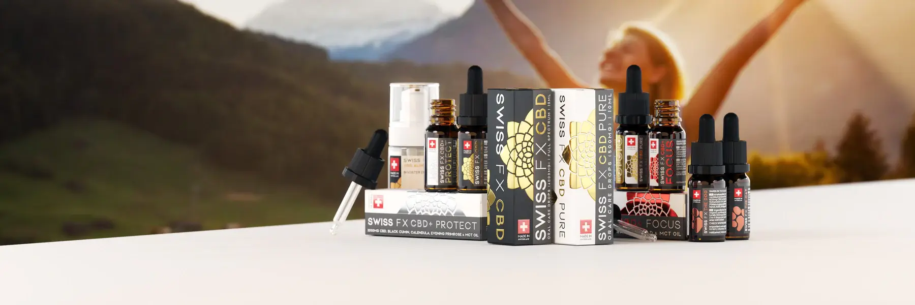 Productos Swiss FX CBD Productos Swiss FX CBD (aceites y cajas) en primer plano, con paisaje de montaña y persona al fondo desenfocada